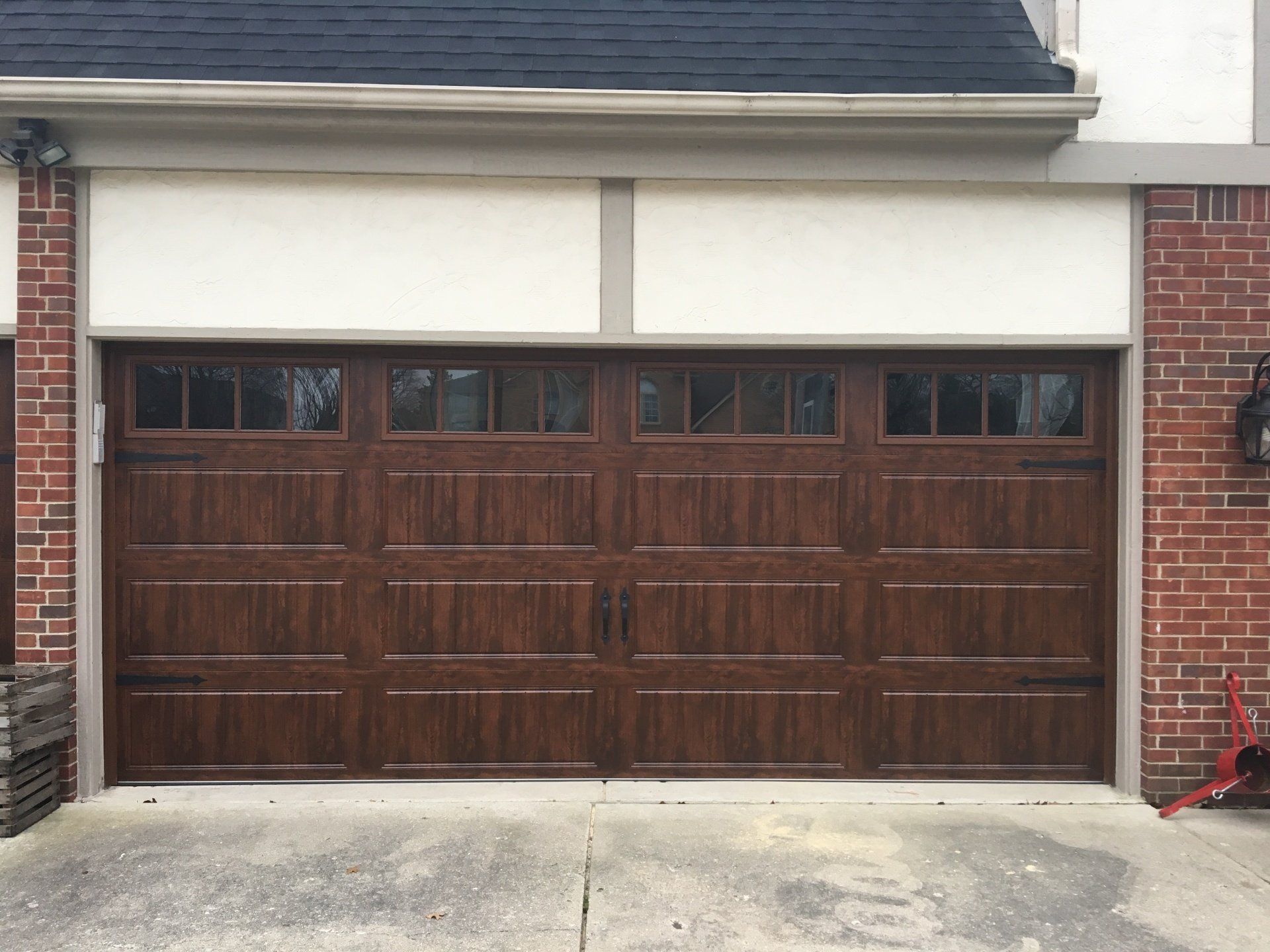 A large wooden garage door is sitting in front of a brick house.