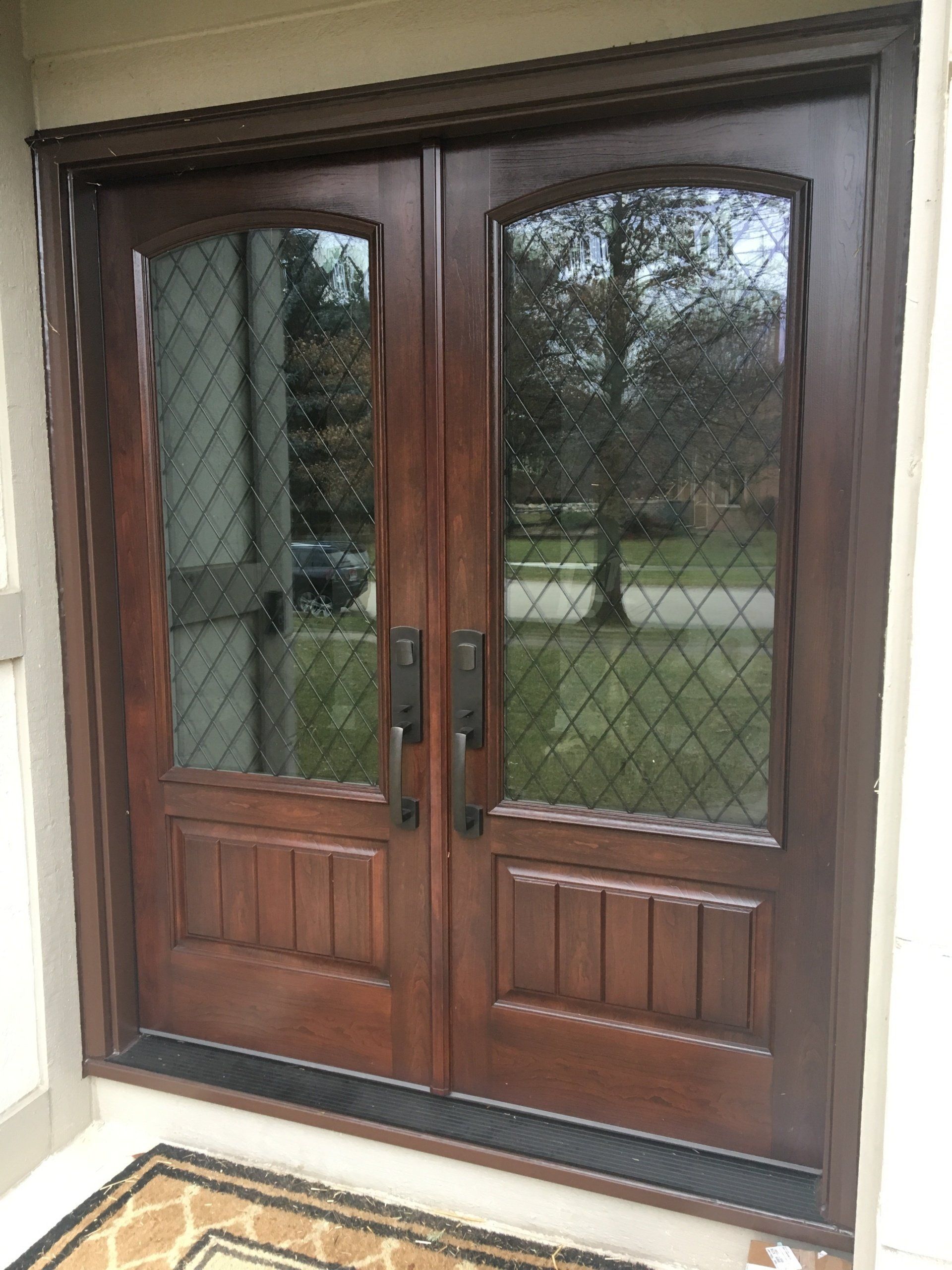 A pair of wooden doors with glass windows on a house.
