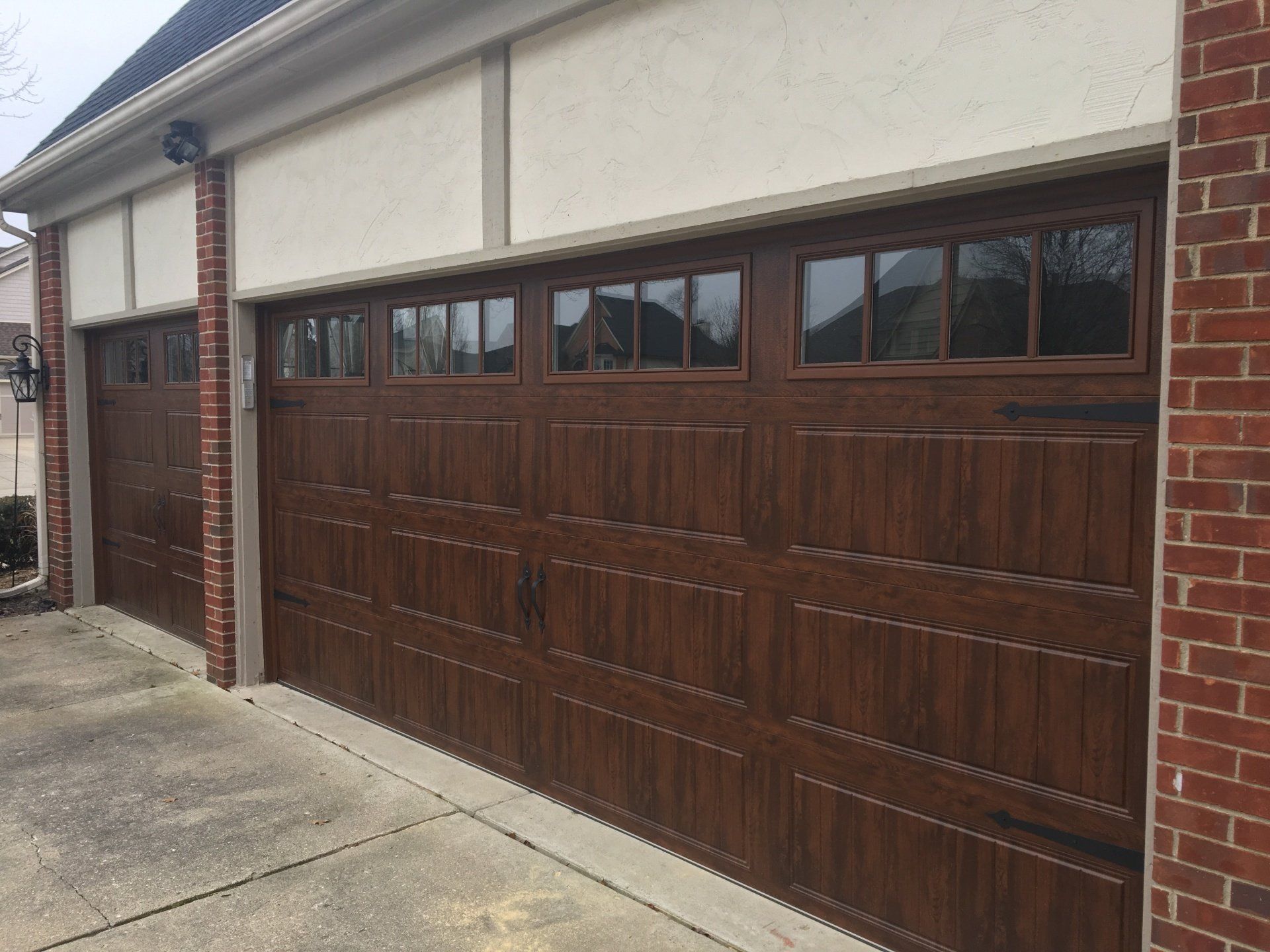 A garage door with a wooden finish and a brick wall.
