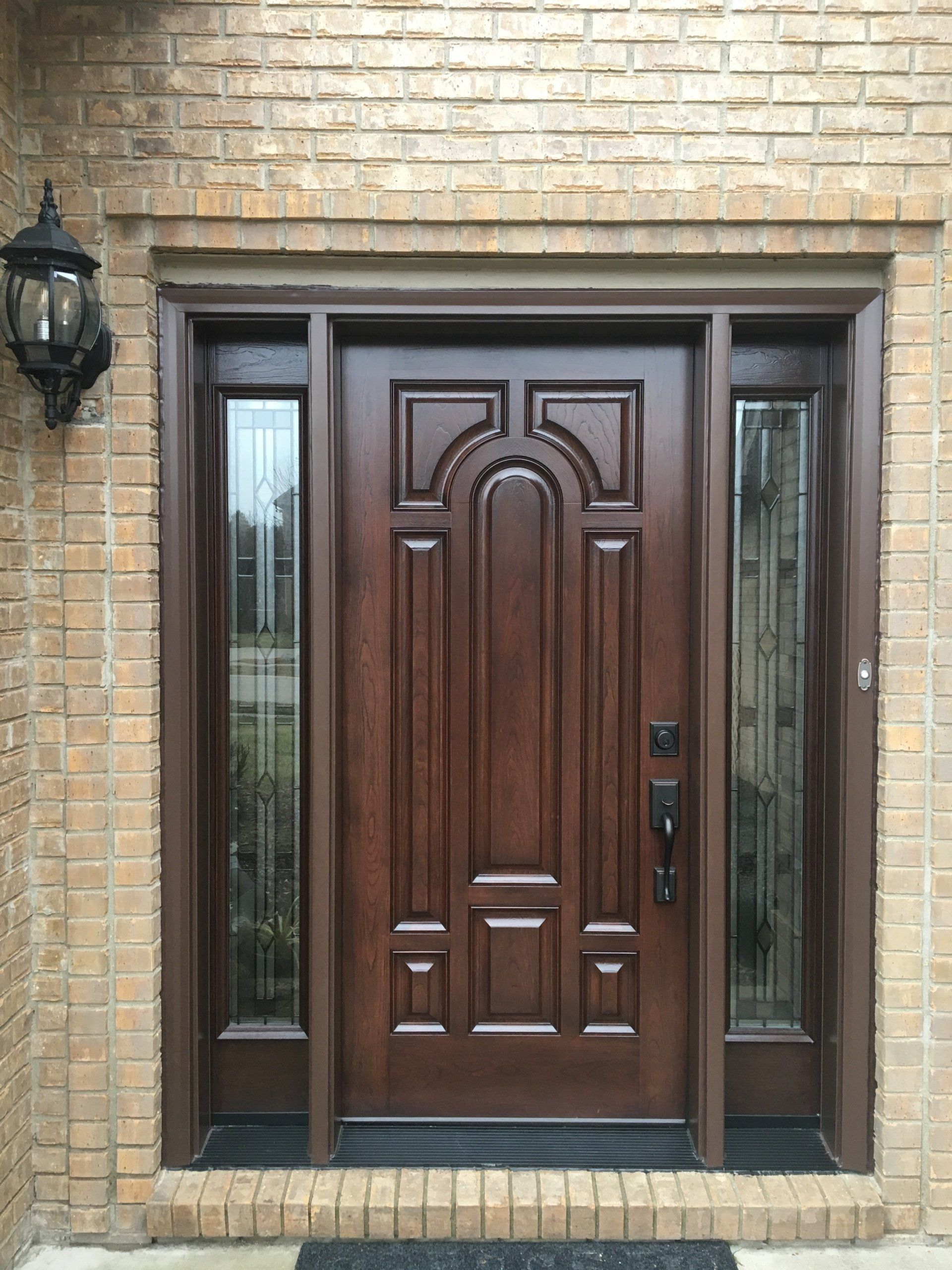 A large wooden door is on a brick building.