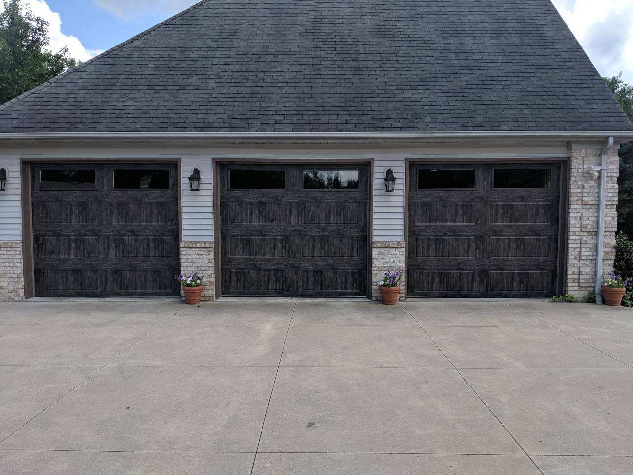 There are three garage doors on the side of a house.