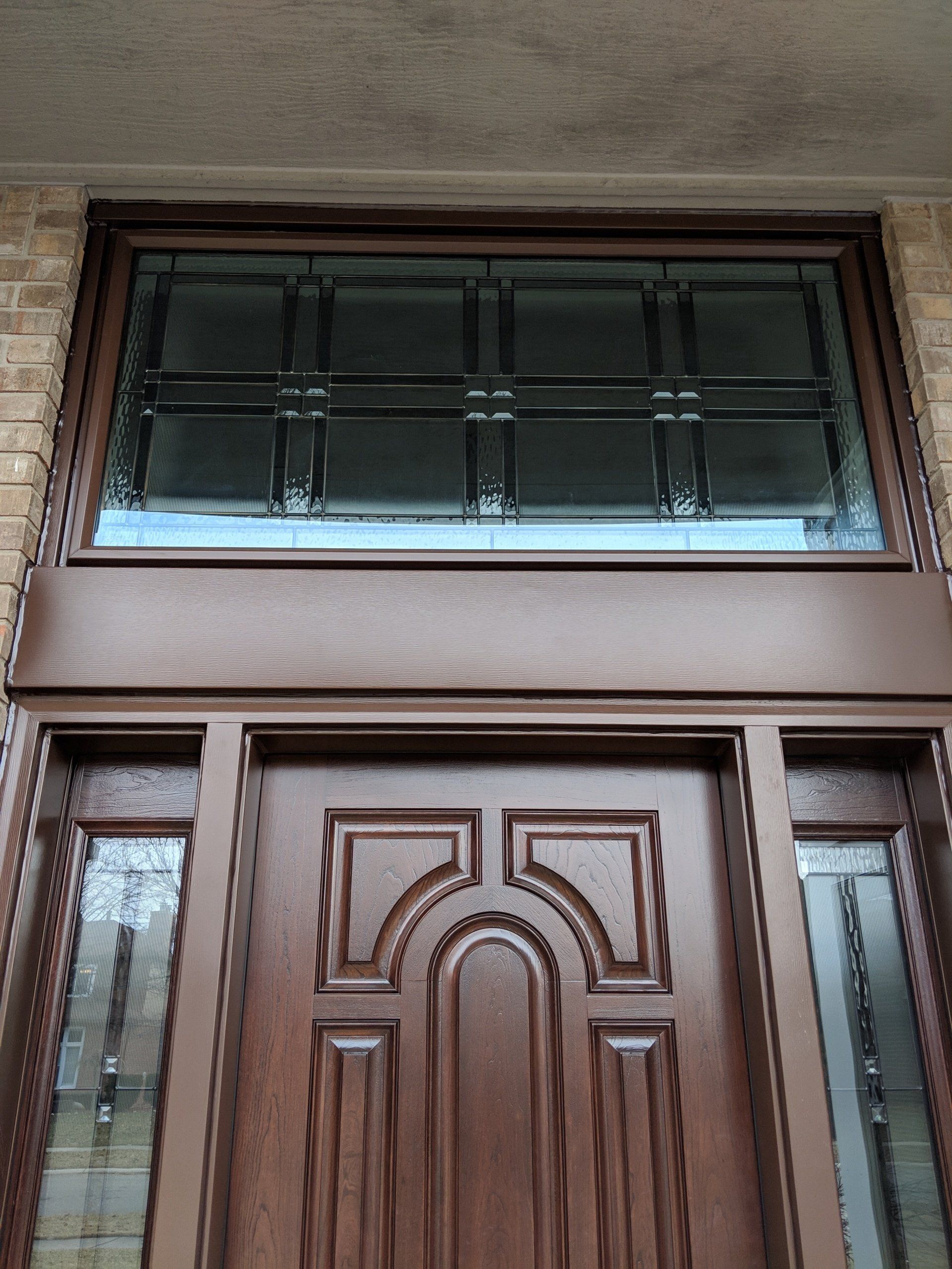 A wooden door with a stained glass window above it