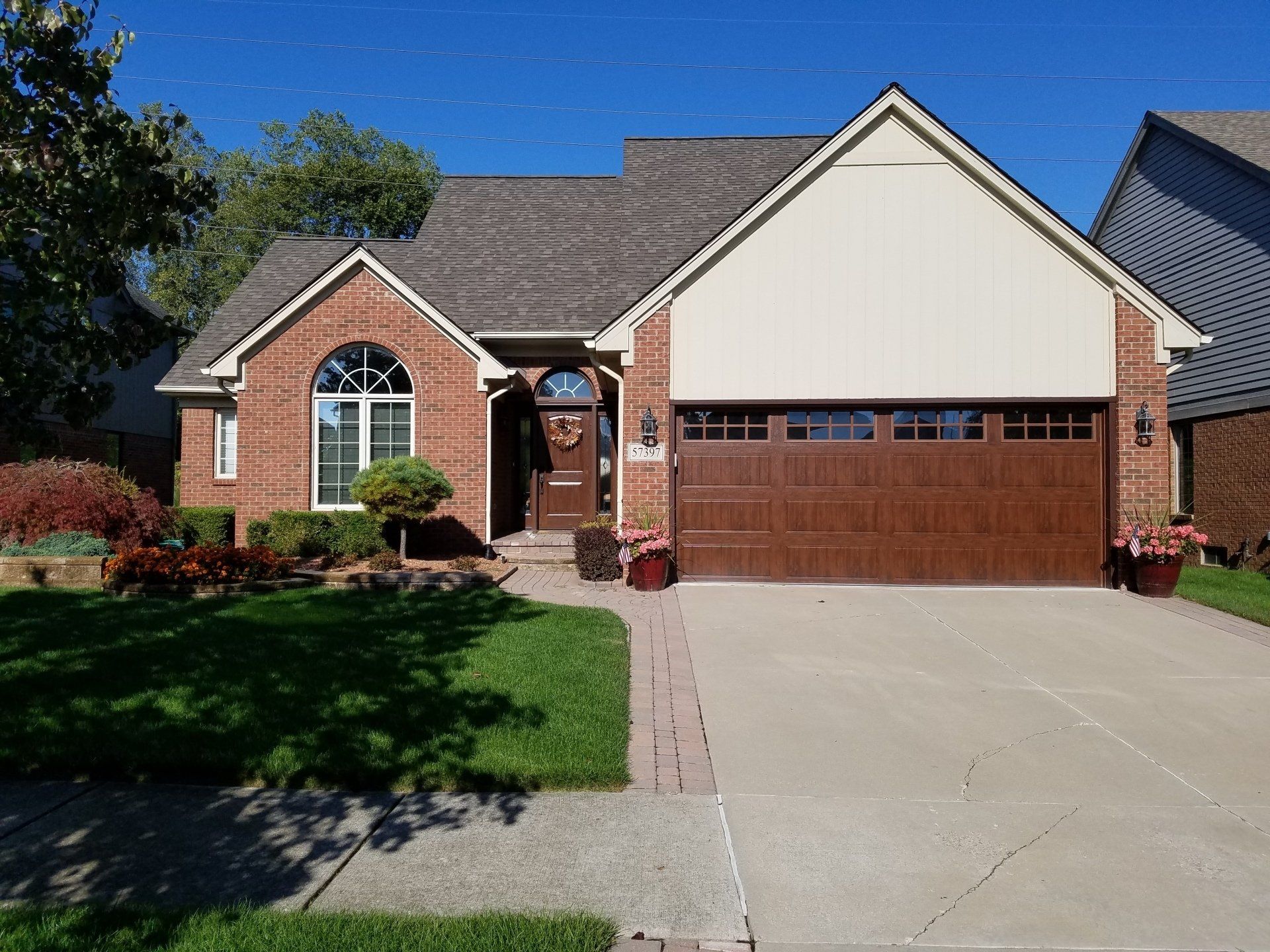 A brick house with a brown garage door and a concrete driveway.