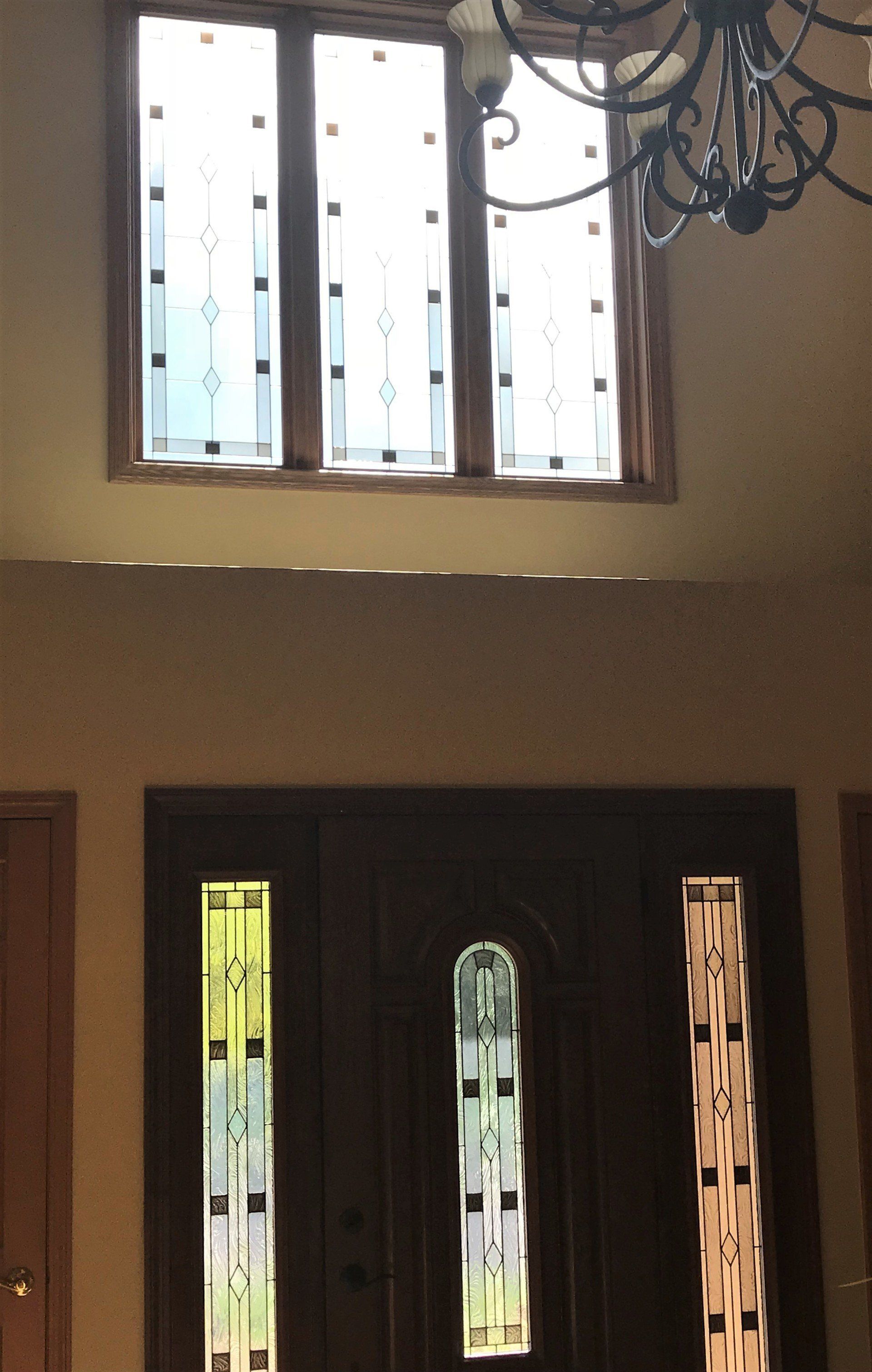 A door with stained glass windows and a chandelier hanging from the ceiling