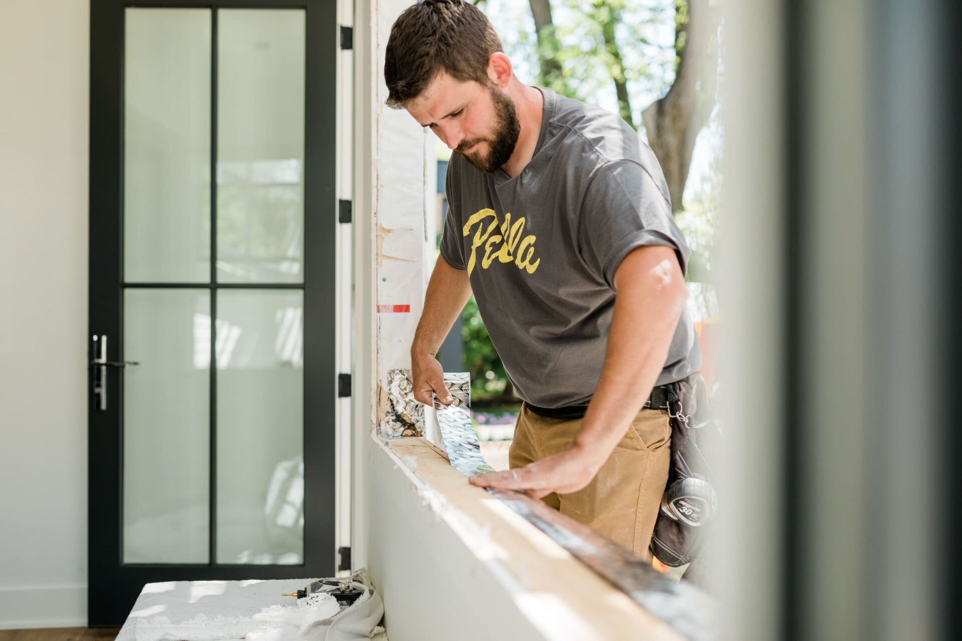 A man is working on a window in a house.