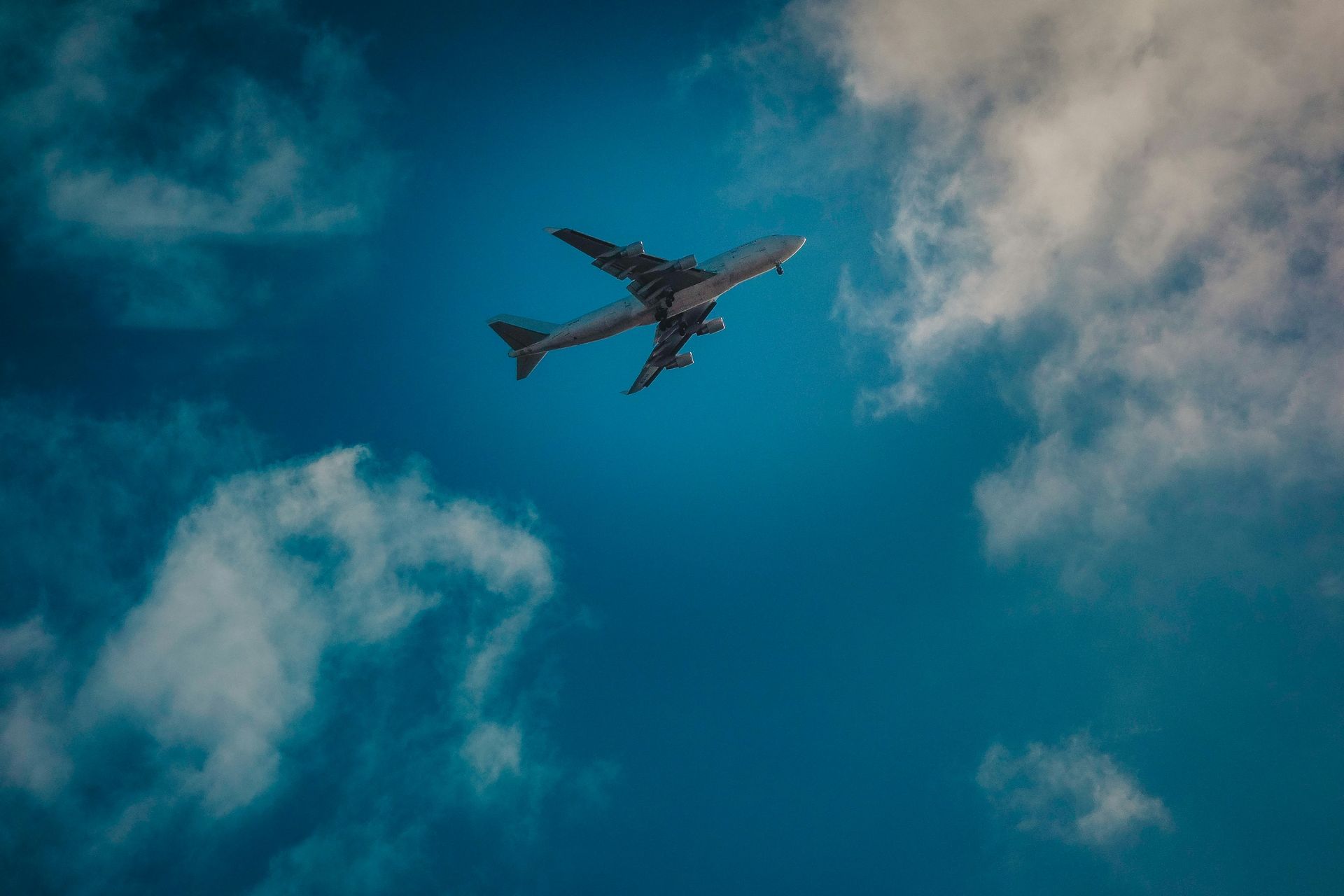 A large passenger jet is flying through a cloudy blue sky.