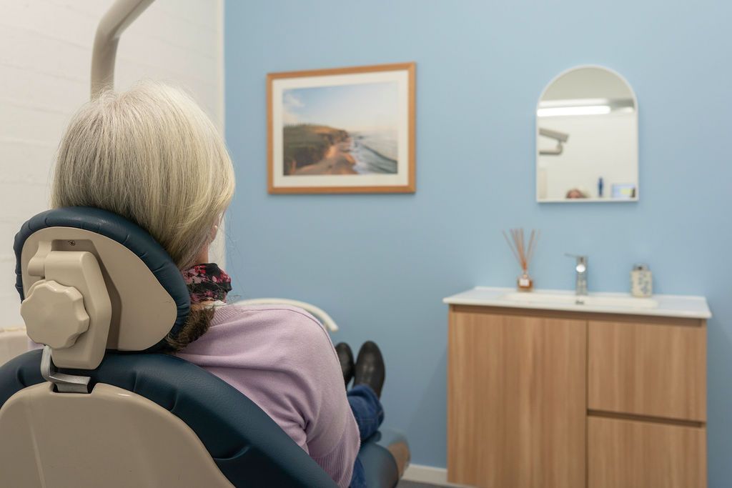 A Person Sits in a Dental Chair, Facing Away — Dr John Salmon, Kiama Family Dental In Kiama, NSW