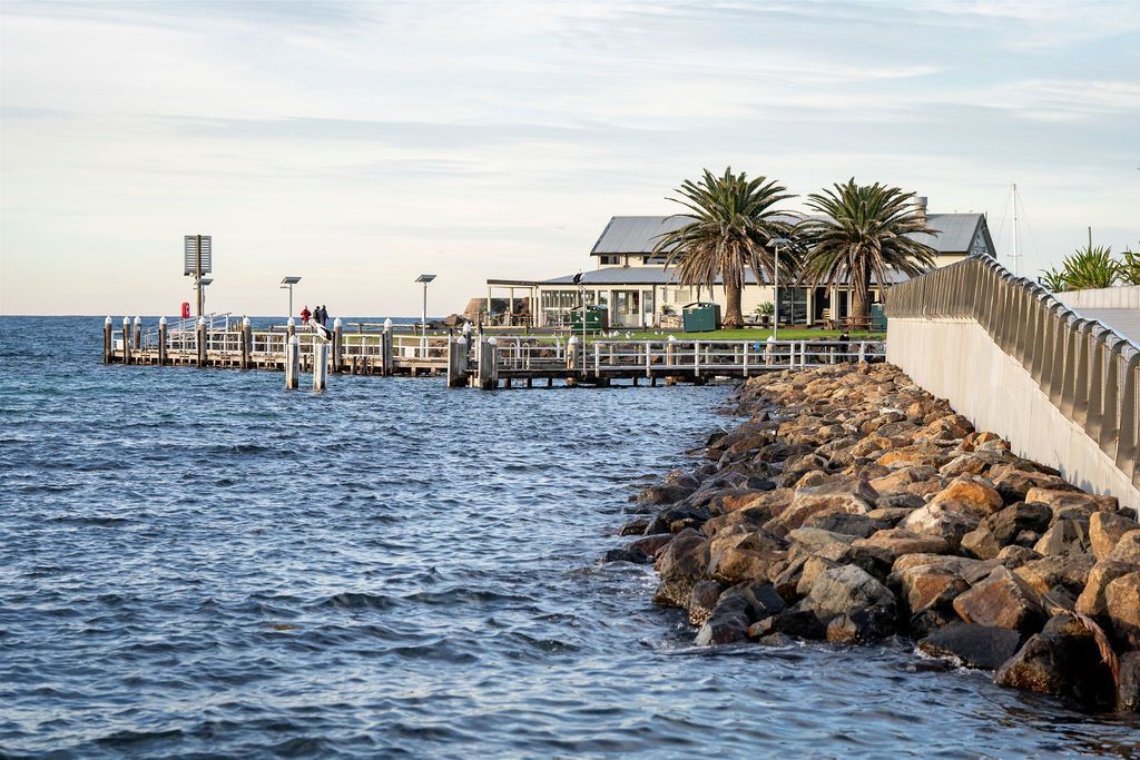 A Pier With a Building and Palm Trees — Dr John Salmon, Kiama Family Dental In Kiama, NSW