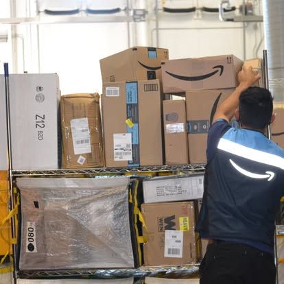 amazon delivery driver organizing packages in back of truck 
