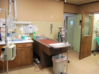 A room with a sink and a trash can in it.