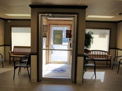 A waiting room with a bench and chairs and a door that is open