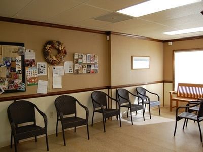A waiting room with chairs and a bench and a wreath on the wall