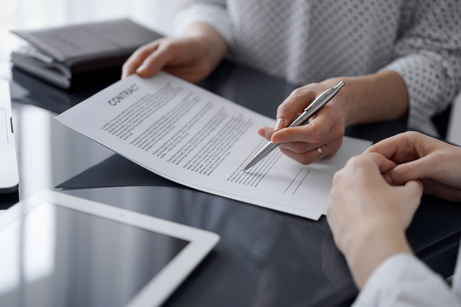 dos personas están sentadas en una mesa firmando un contrato .
