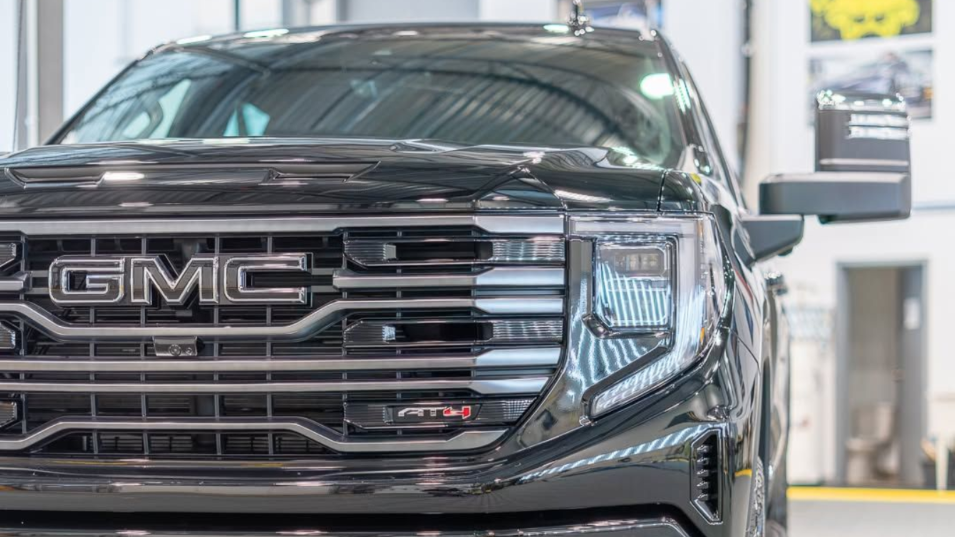 Black GMC truck front view with large grill and headlights, tow hook visible.