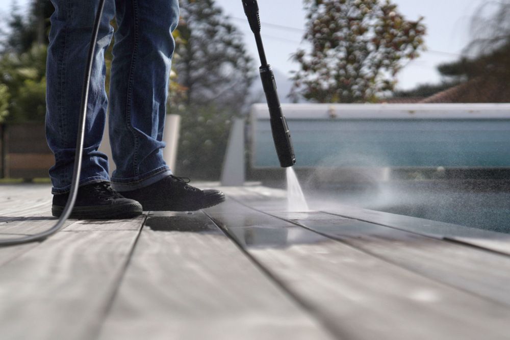 A Person is Cleaning a Wooden Deck With a High Pressure Washer — Magic Wand Roof Restoration & Painting in Mermaid Beach, QLD