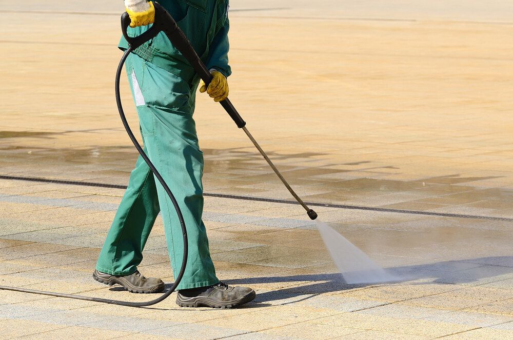 A Man is Using a High Pressure Washer to Clean a Patio — Magic Wand Roof Restoration & Painting in Mermaid Beach, QLD