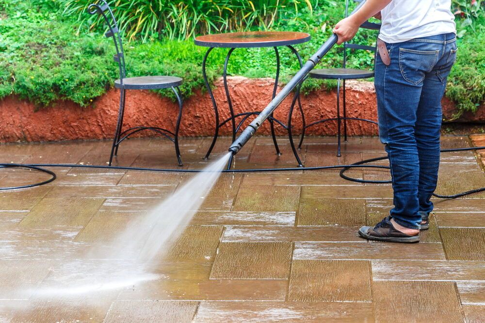 A Man is Using a High-pressure Washer to Clean the Ground— Magic Wand Roof Restoration & Painting in Mermaid Beach, QLD