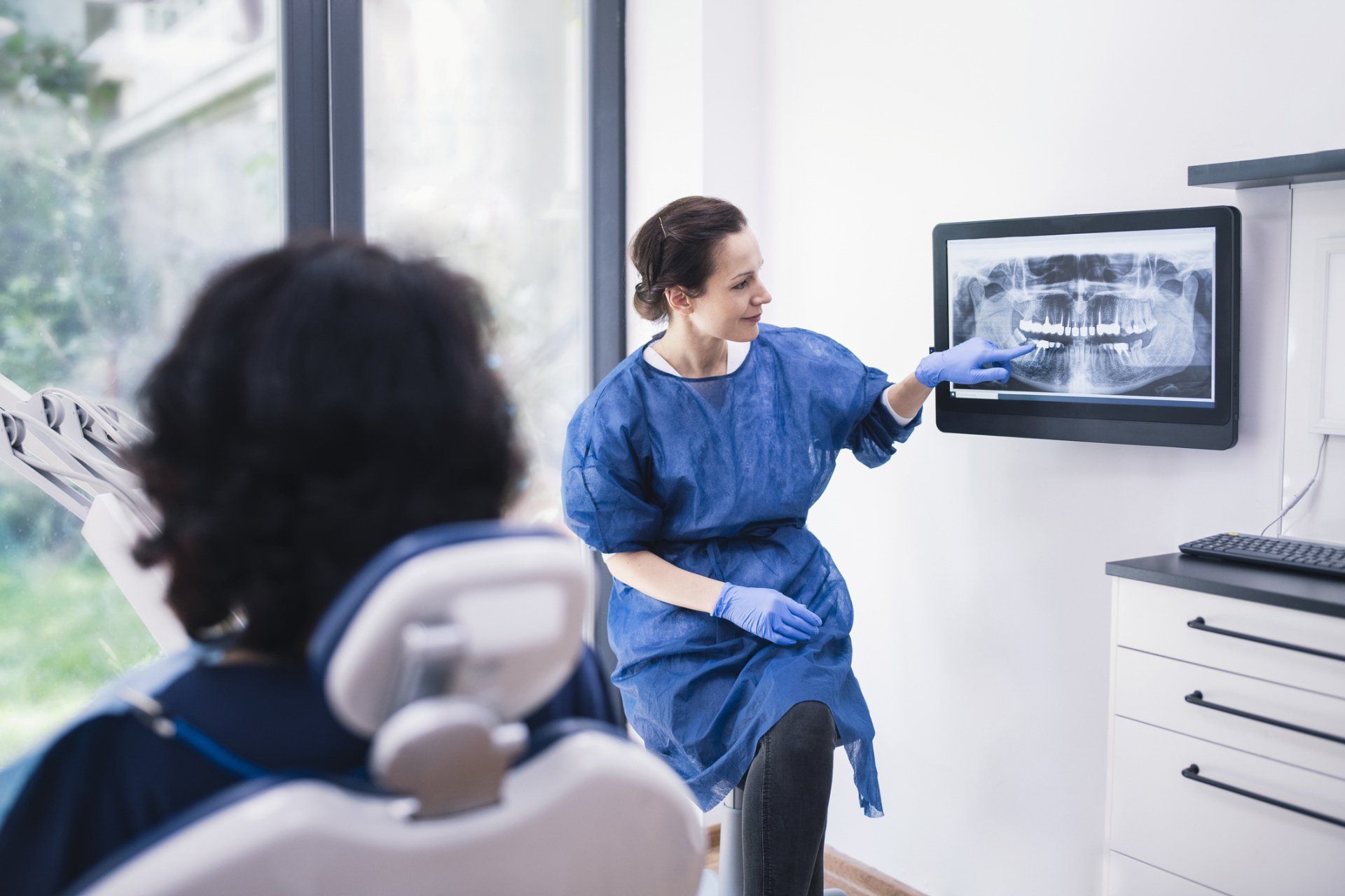 Female dentist explaining tooth x-rays to an unrecognizable patient — Madison, WI — East Grove Dental