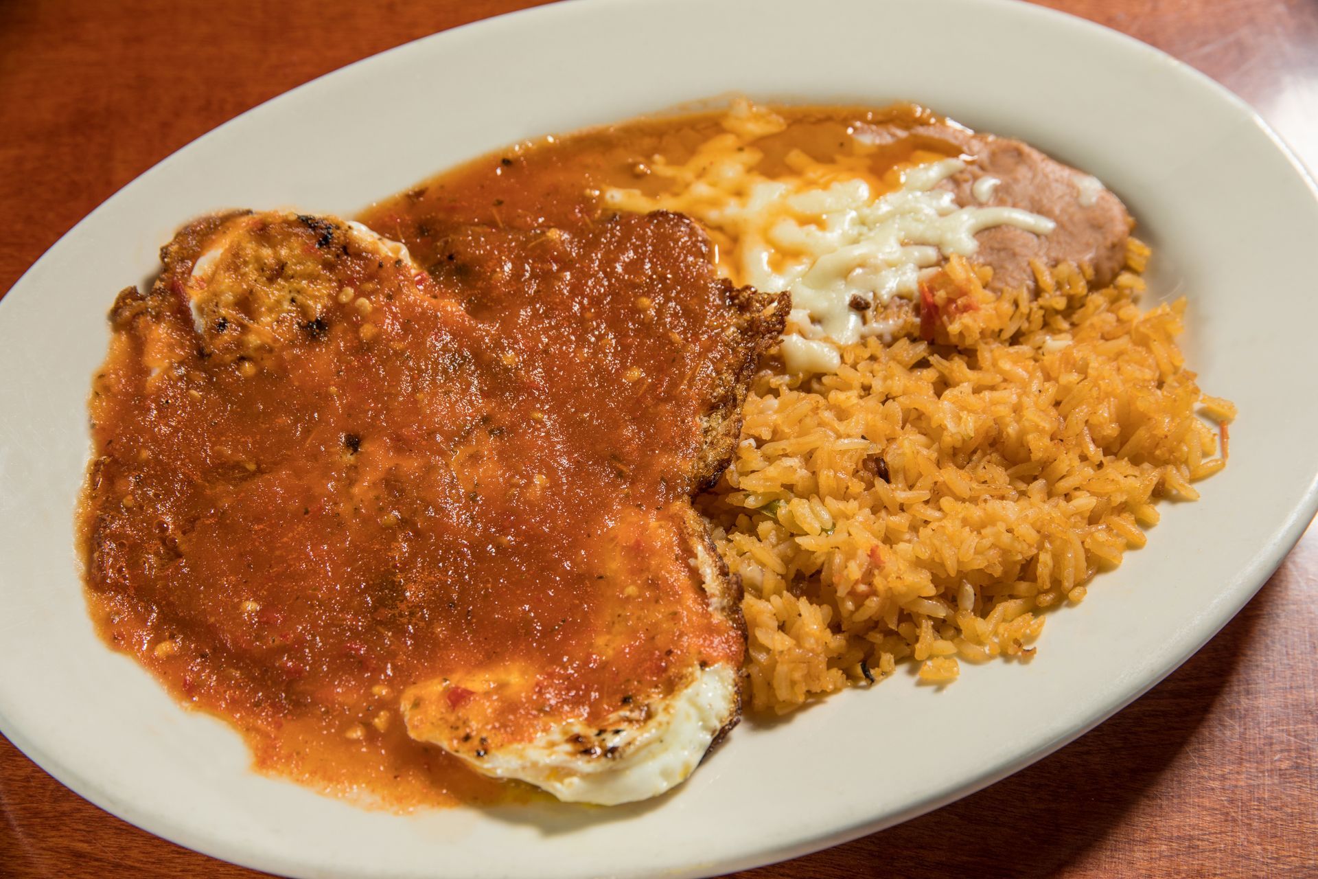 A plate of mexican food with rice and meat on a table.