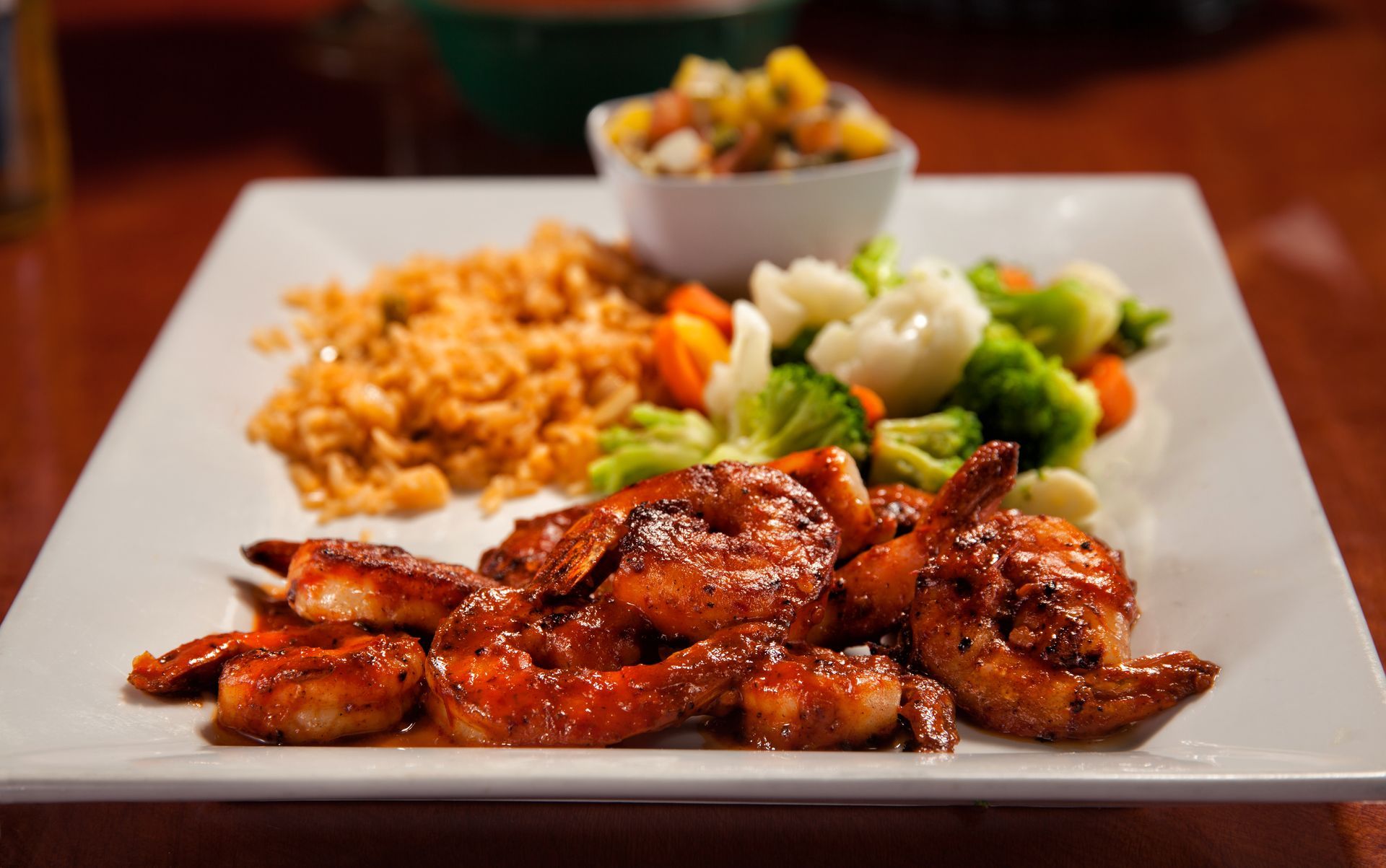 A white plate topped with shrimp , rice and vegetables.