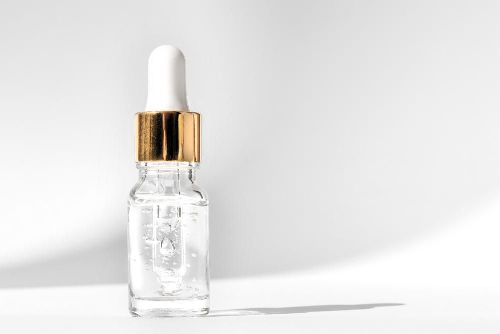 A Small Bottle Of Serum With A Dropper On A White Surface — Mackay Skin Clinic In North Mackay, QLD