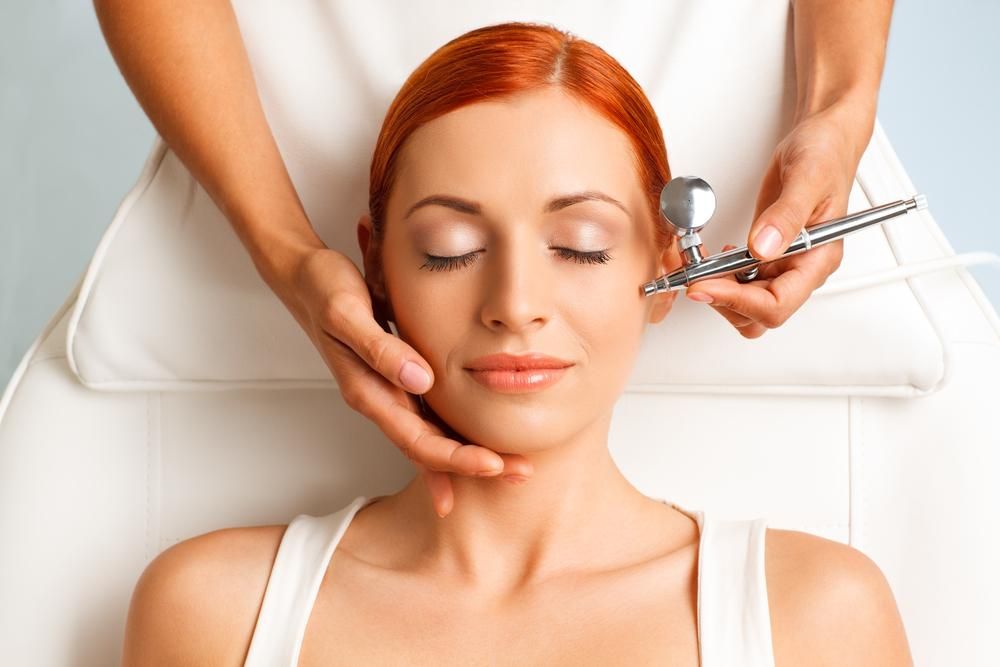 A Woman Is Getting An Airbrush Treatment On Her Face — Mackay Skin Clinic In North Mackay, QLD