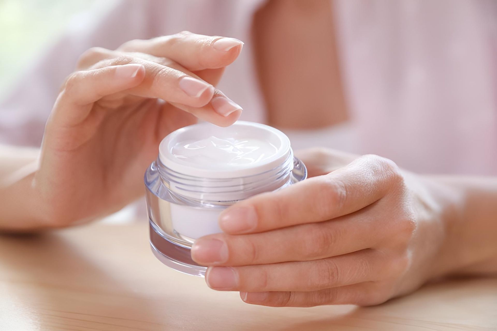 A Woman Is Holding A Jar Of Cream In Her Hands — Mackay Skin Clinic In North Mackay, QLD