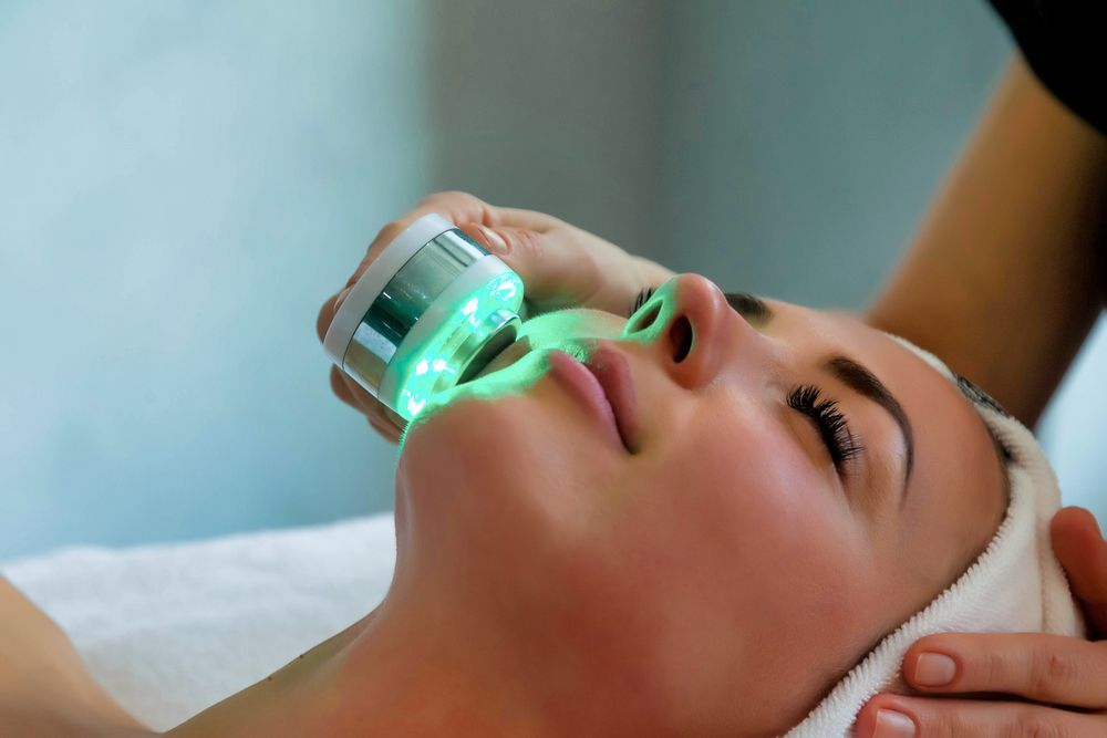 A Woman Is Getting A Facial Treatment With Green Lights On Her Face — Mackay Skin Clinic In North Mackay, QLD
