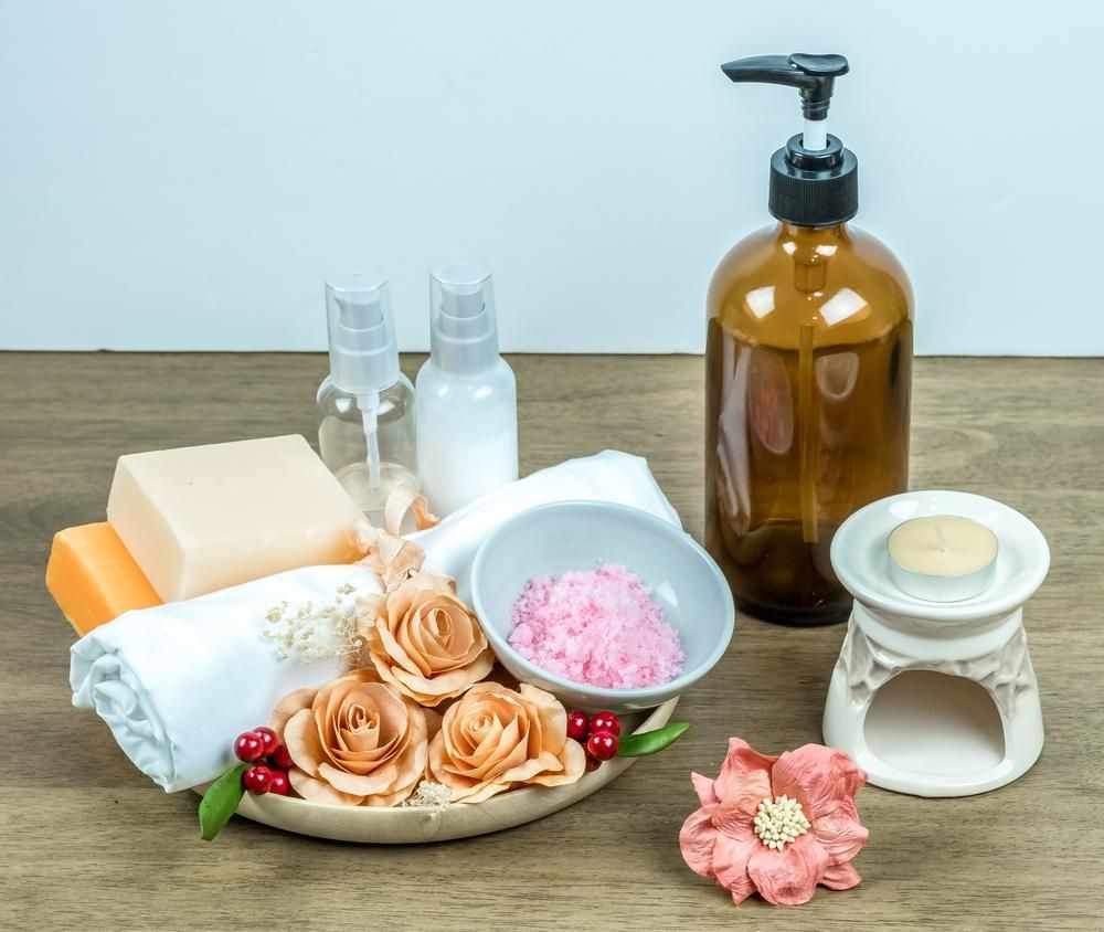A Wooden Table Topped With Soap, Lotion, Candles, And Flowers — Mackay Skin Clinic In North Mackay, QLD