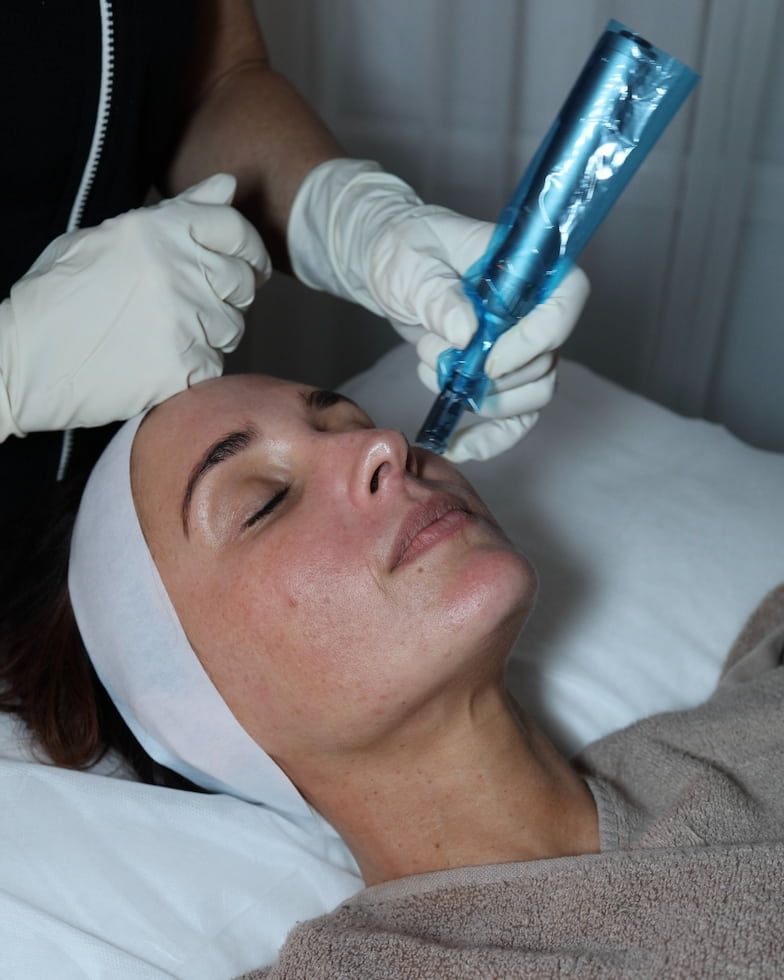 A Woman Lies on a Spa Bed With Closed Eyes, Receiving a Facial Treatment