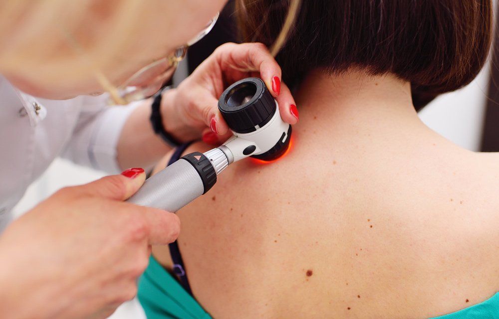 A Doctor Is Examining A Woman 's Back With A Magnifying Glass — Mackay Skin Clinic In North Mackay, QLD