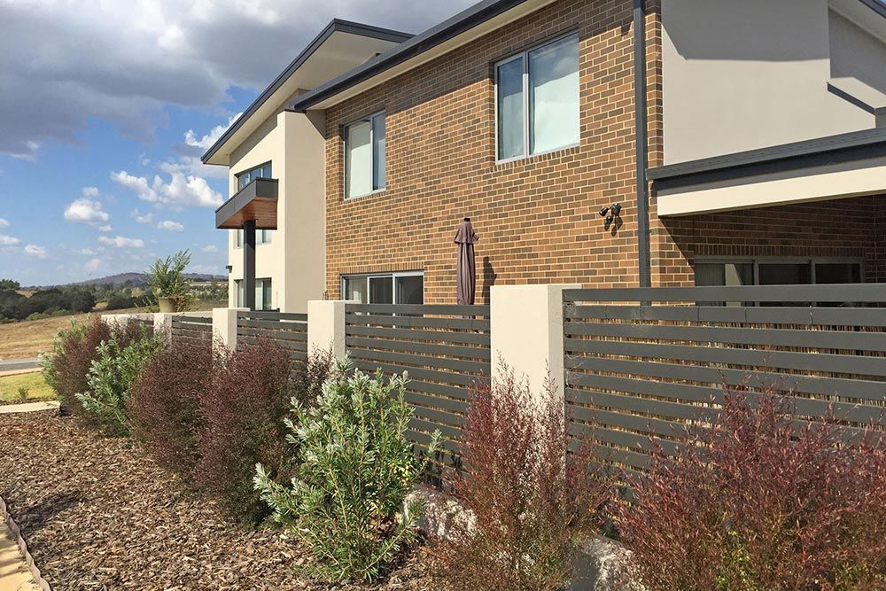 A Large Brick House With a Fence in Front of It — Imperial Build Co. in  Coombs, ACT