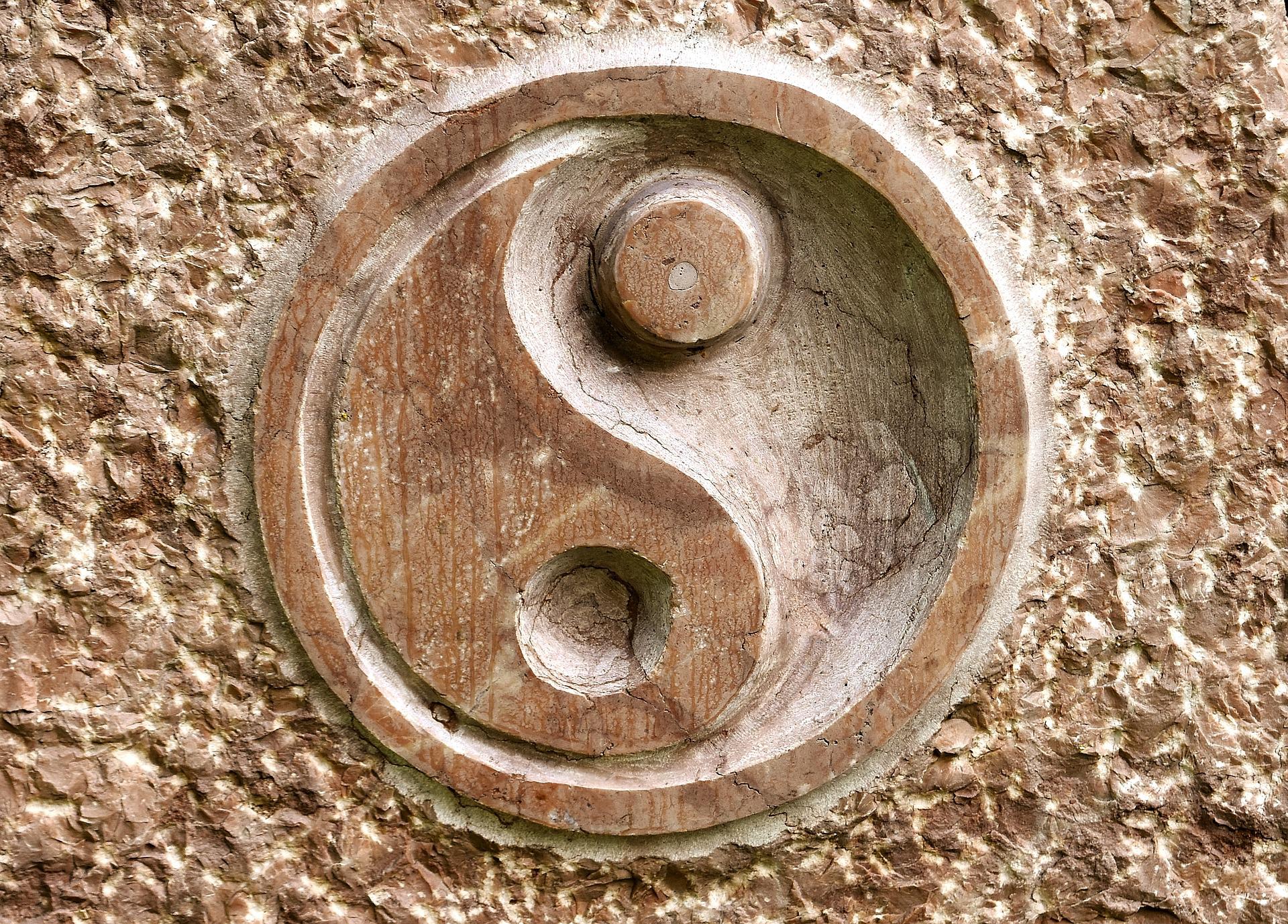 Un gros plan d'une sculpture en pierre d'un symbole yin yang sur un mur.