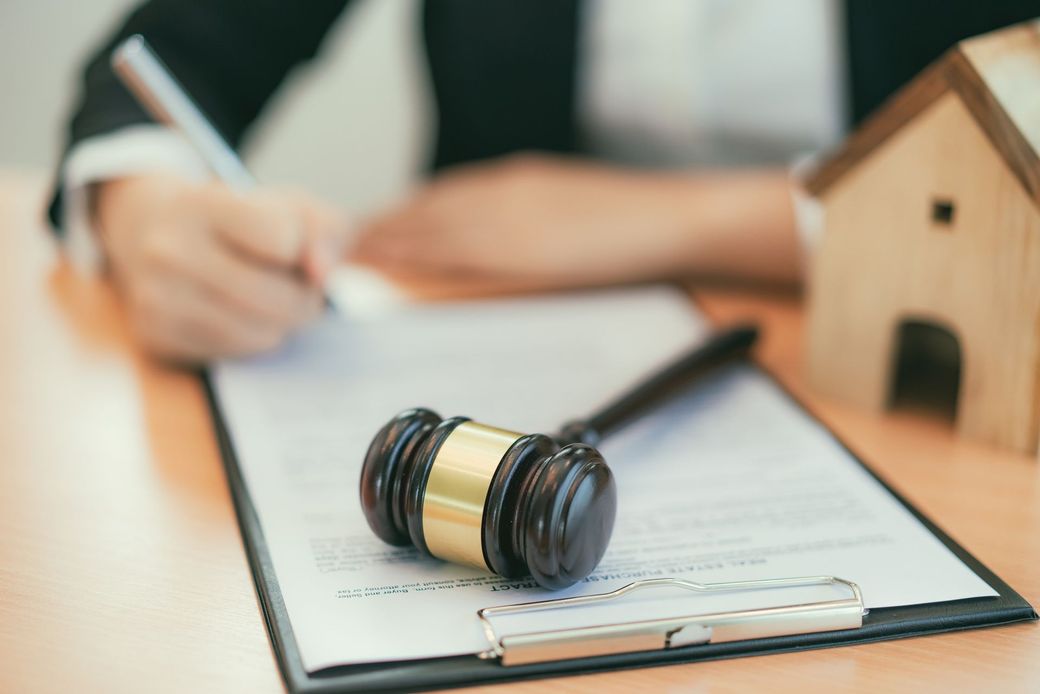 Una persona sta scrivendo su un blocco per appunti accanto al martelletto di un giudice.