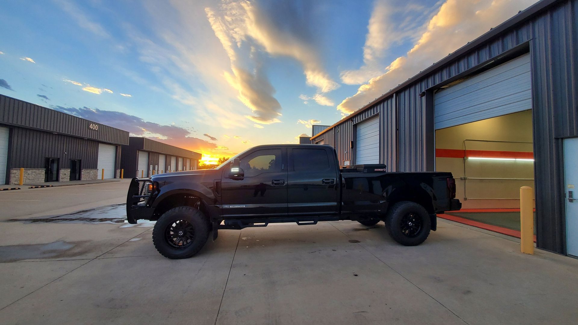 A black truck is parked in front of a building.