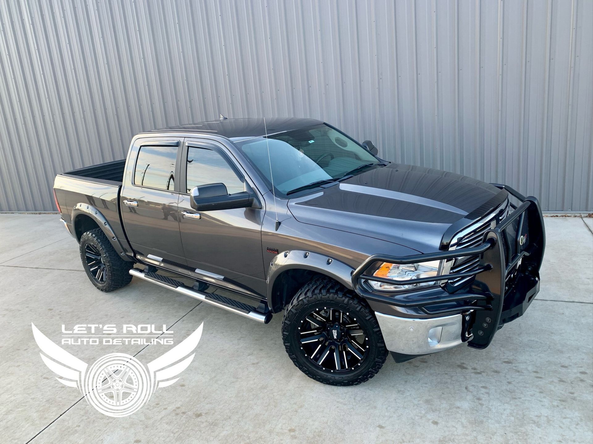 A gray dodge ram truck is parked in front of a building.