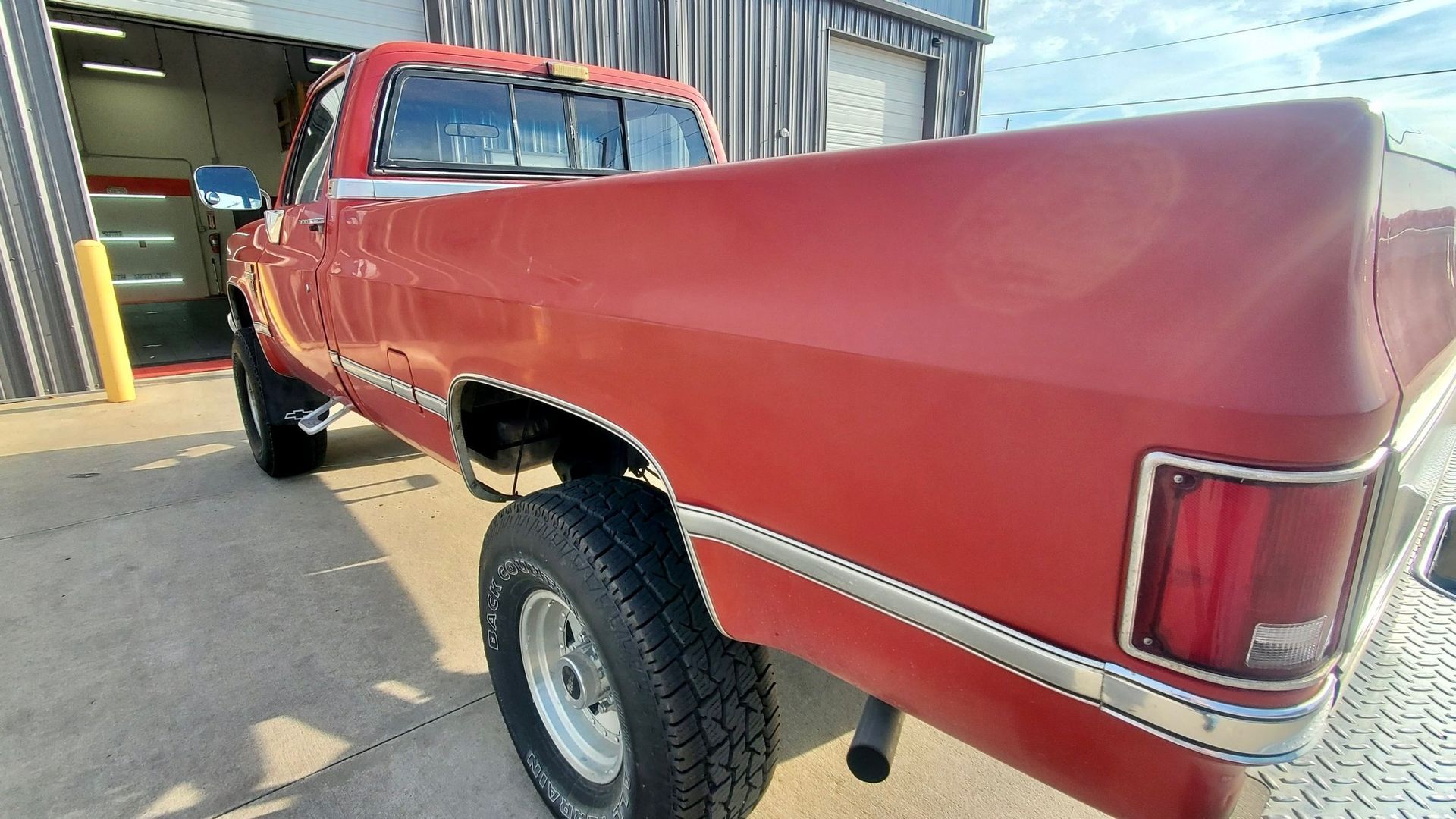 A red truck is parked in front of a garage.