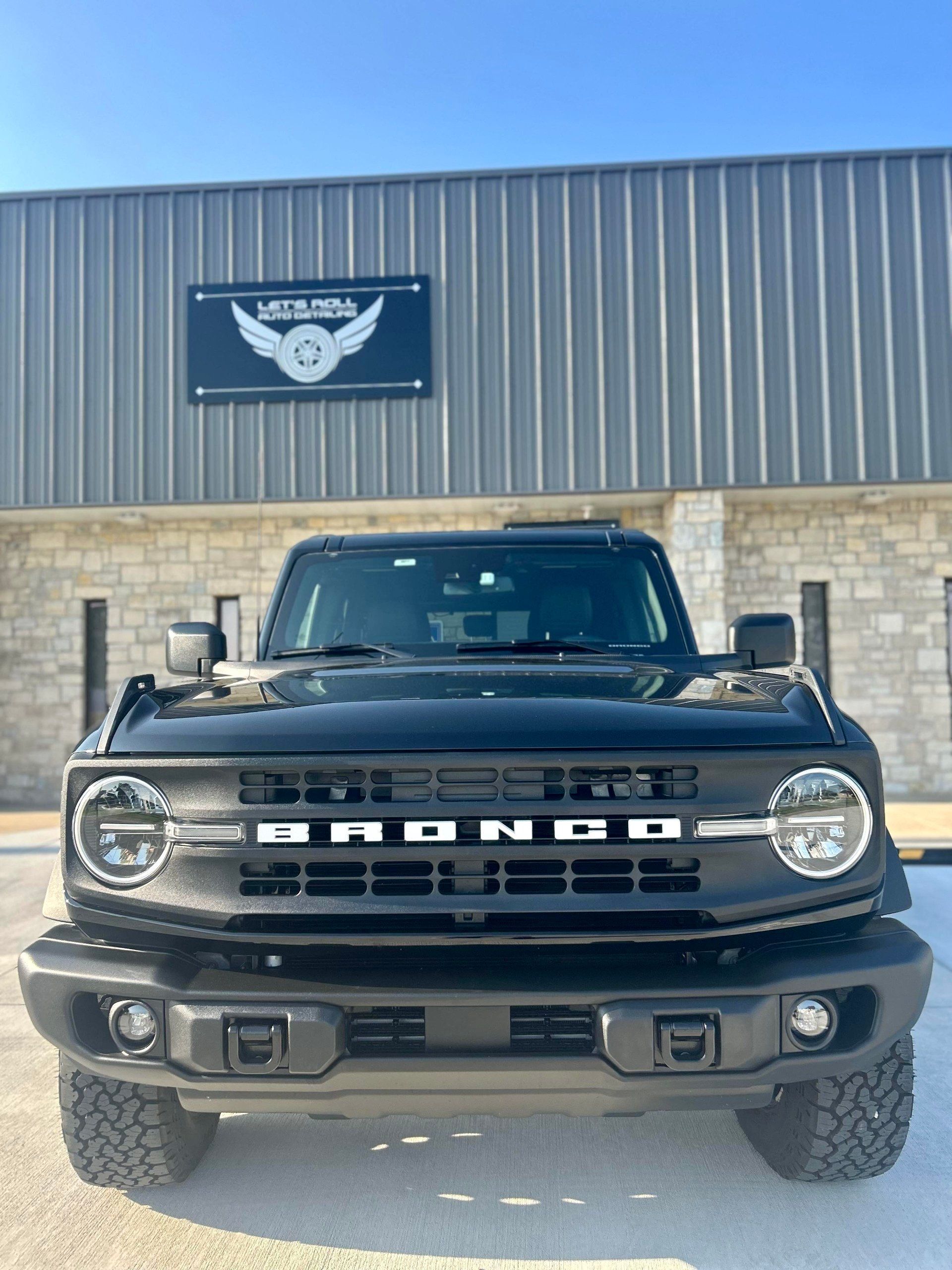 A black bronco is parked in front of a building.