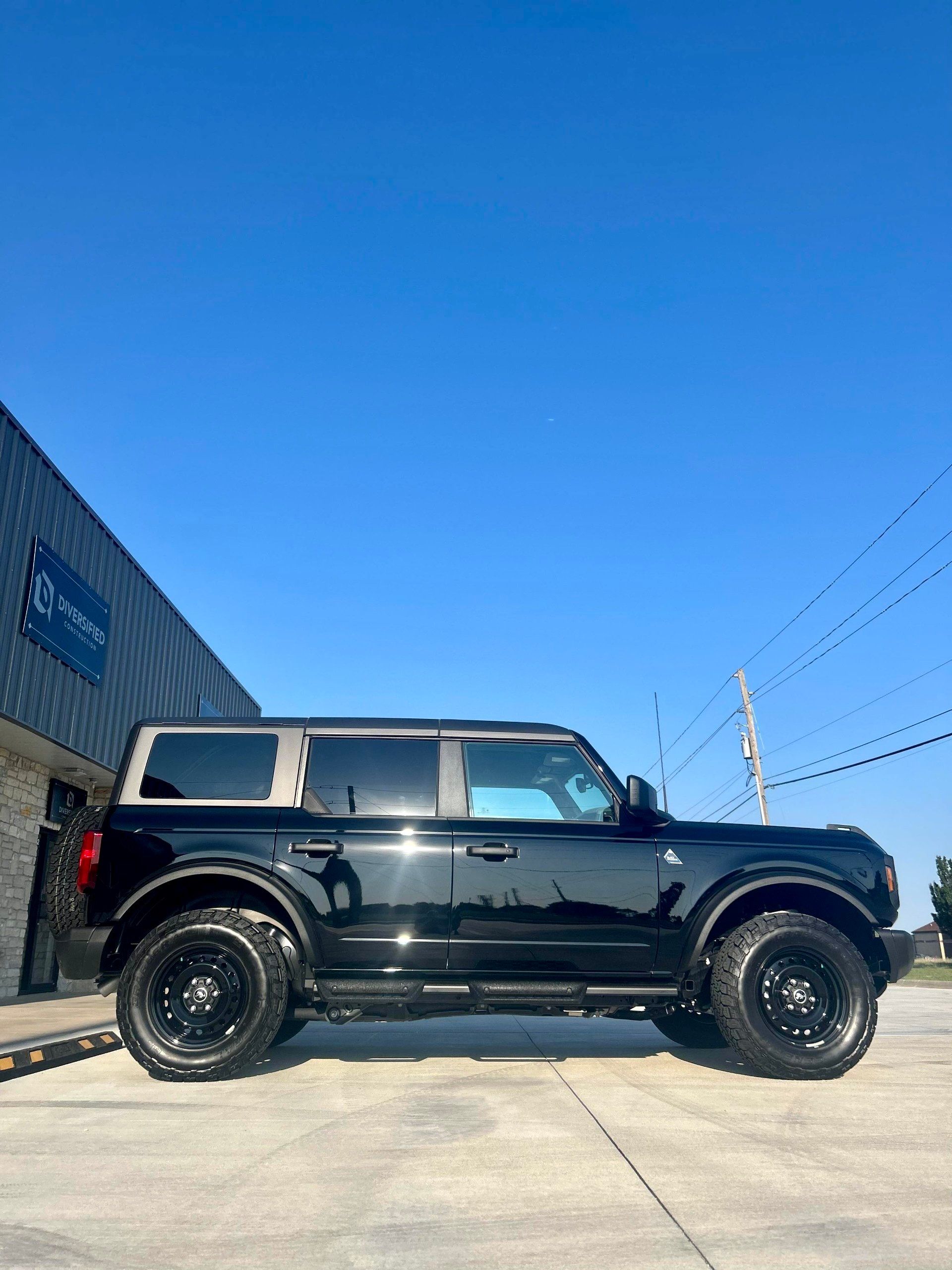 A black ford bronco is parked in front of a building.