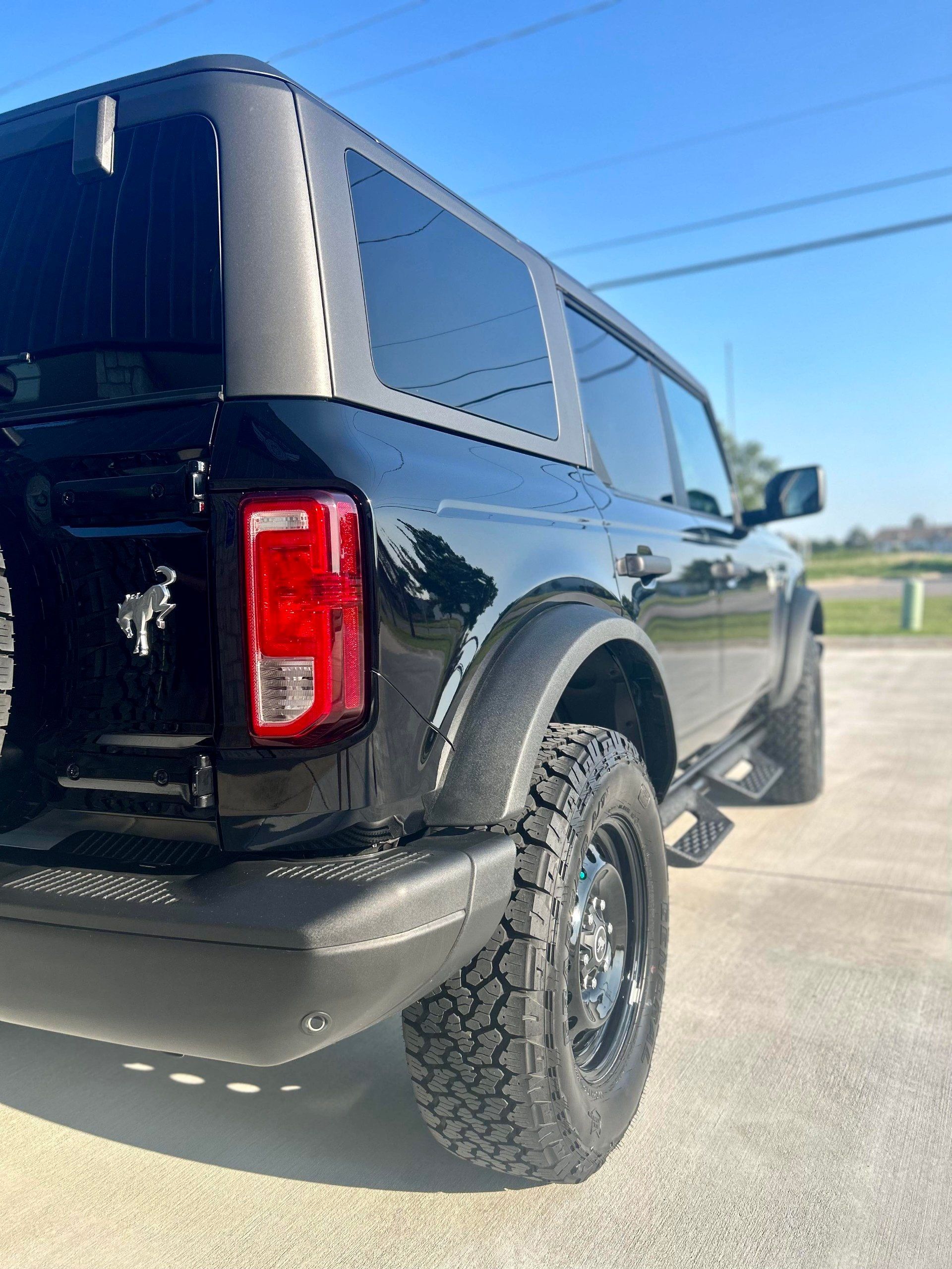 A black ford bronco is parked on the side of the road.