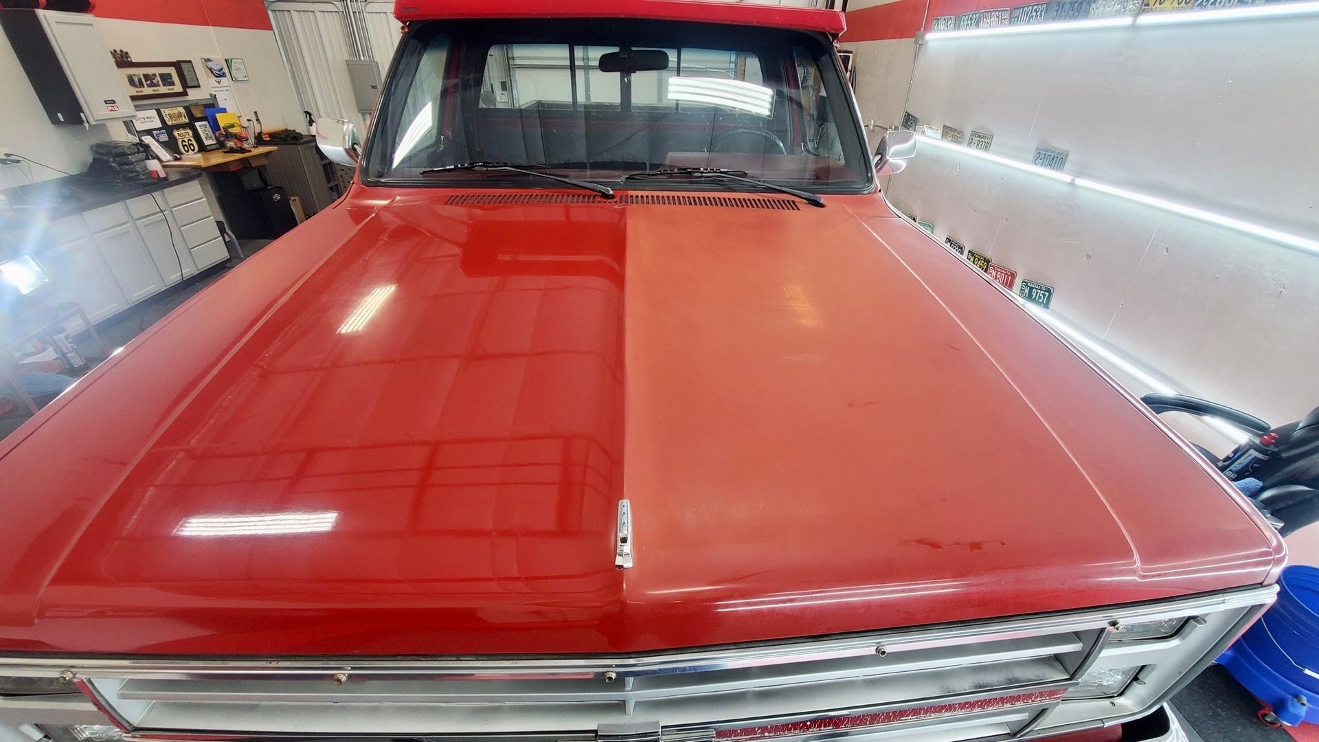 A red truck is parked in a garage next to a white wall.