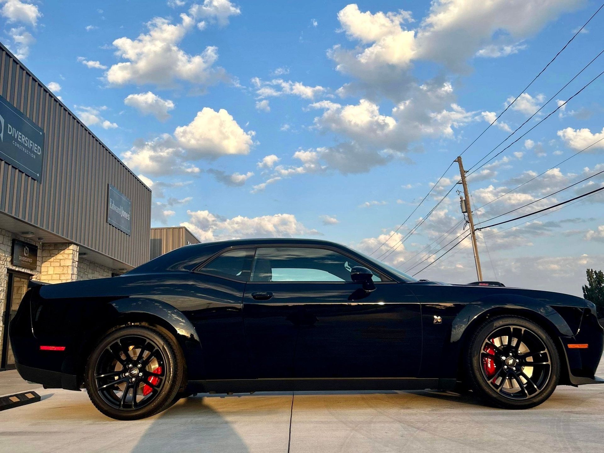 A black dodge challenger is parked in front of a building.