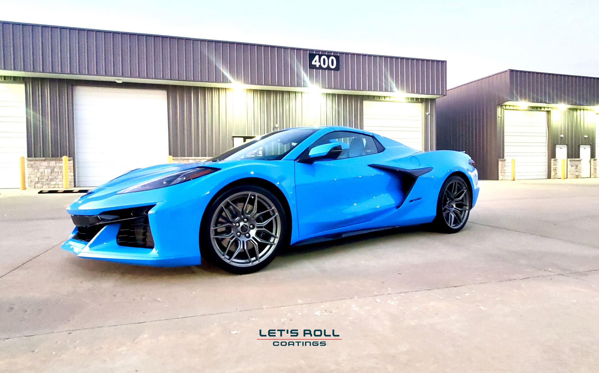 A blue sports car is parked in front of a building.