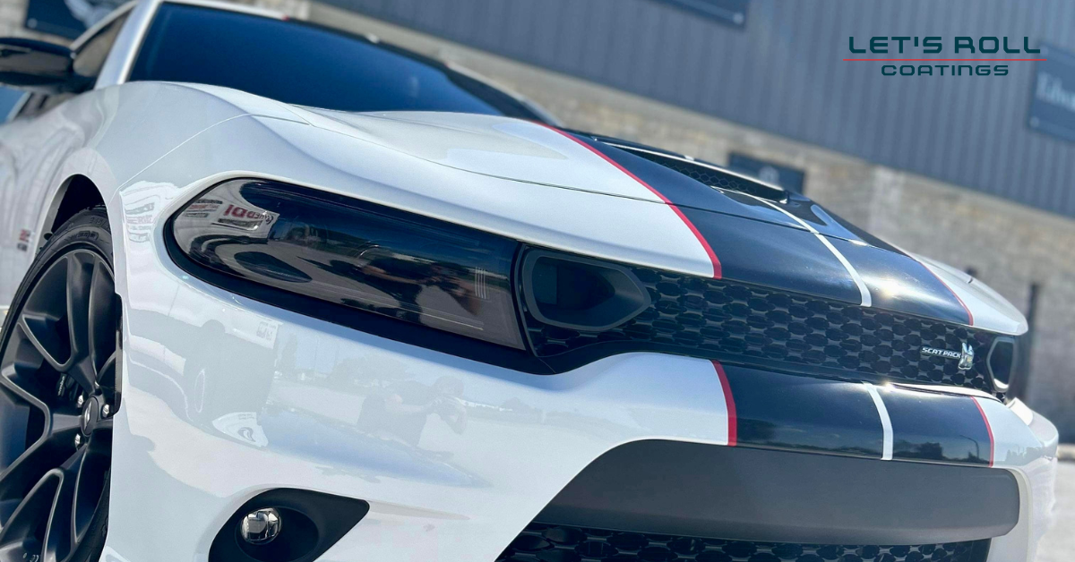 A white dodge charger with a black and red stripe on the hood is parked in front of a building.