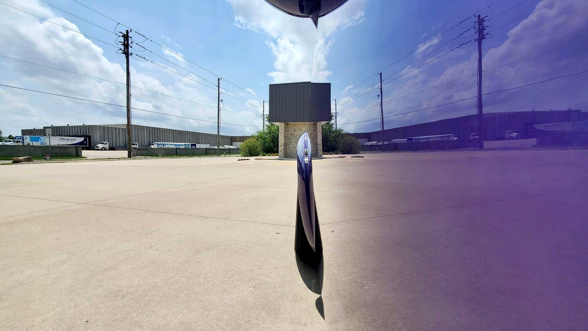 A purple car is parked in a parking lot with a building in the background.