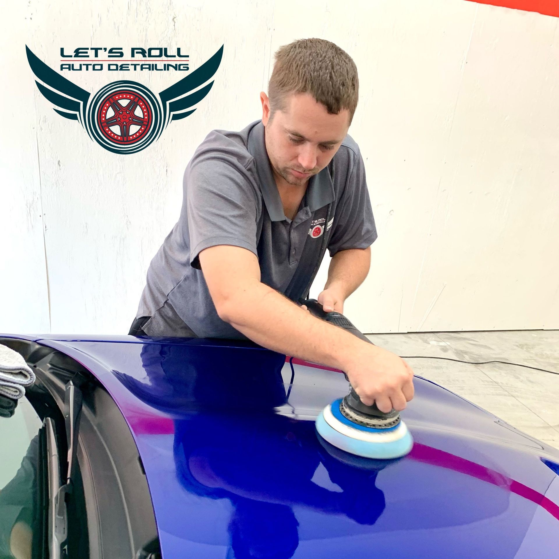 A man is cleaning a blue car with a cloth