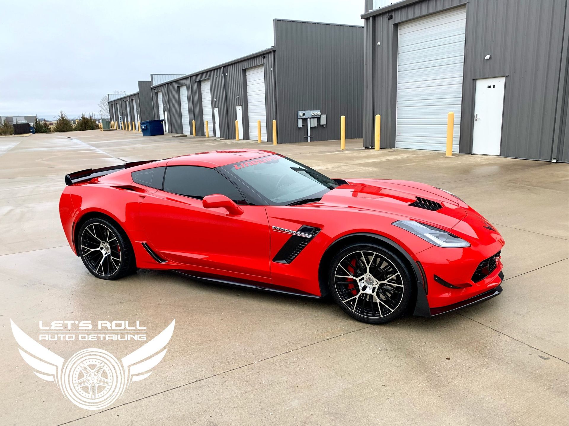 A red corvette is parked in a parking lot in front of a building.