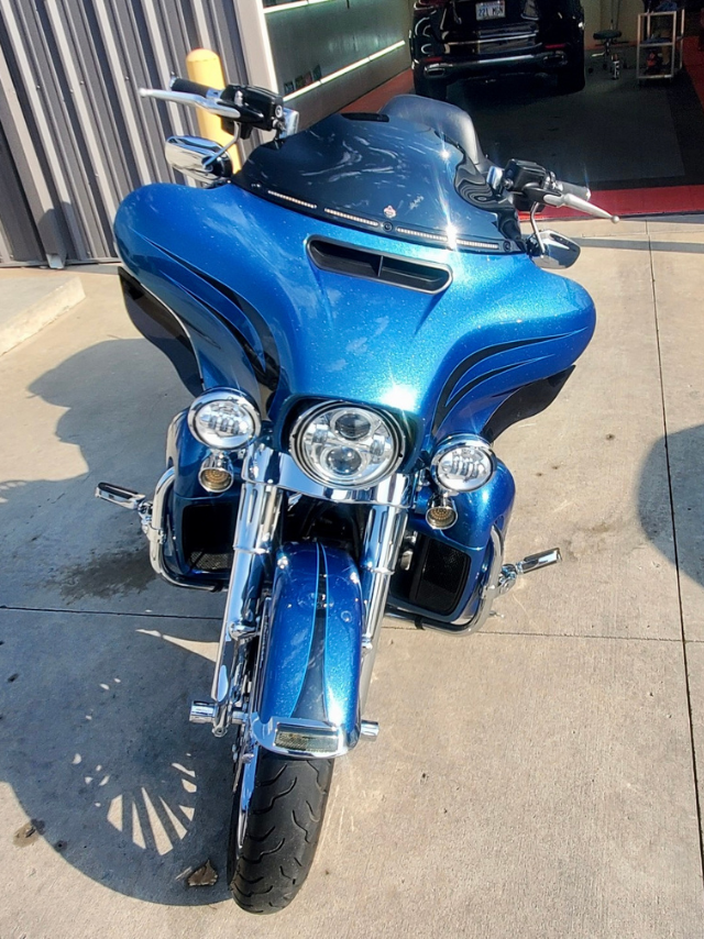 A blue harley davidson motorcycle is parked on the sidewalk in front of a building.