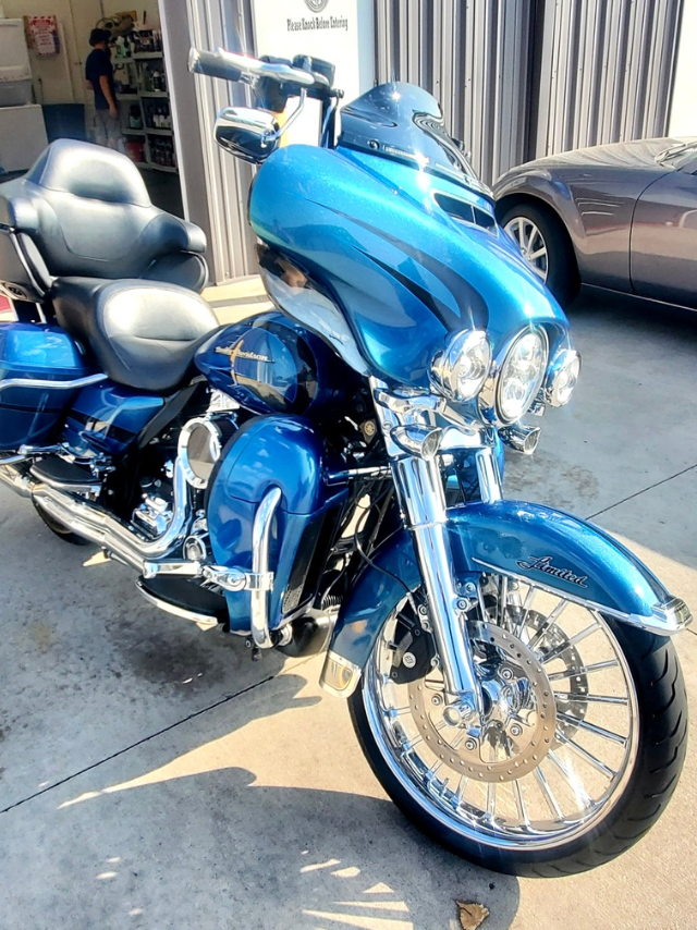 A blue harley davidson motorcycle is parked in front of a building