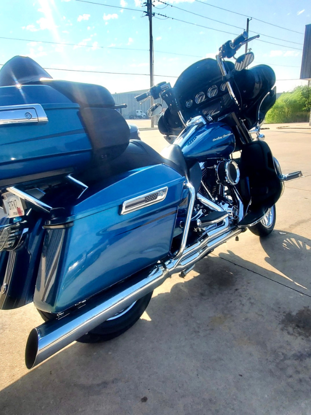 A blue harley davidson motorcycle is parked in a parking lot